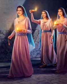 three women dressed in pink robes holding candles