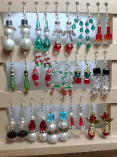 there is a rack with many different earrings on the shelf and one has a red glass bead hanging from it