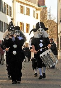 some people are walking down the street with costumes on and one is holding a drum