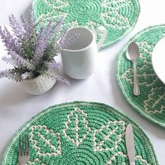 the placemats are green and white with crocheted designs on them, along with silverware