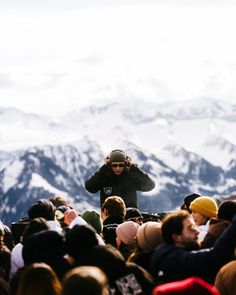 a man standing in front of a large group of people on top of a snow covered mountain