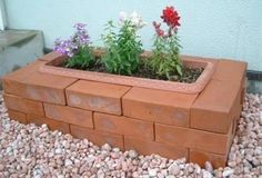 a brick planter with flowers growing out of it