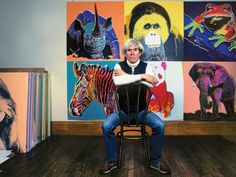 a man sitting on a chair in front of some paintings and pictures with zebras