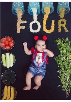 a baby sitting in front of some vegetables and fruit