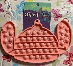 a pink plastic tray with holes in the shape of a teapot on top of a table