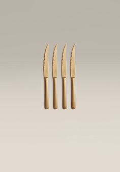 three knives with gold handles on a gray background