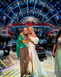 two women standing next to each other in front of a stage