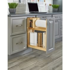 an open cabinet in a kitchen with a laptop on the counter