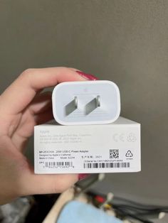 a person holding a white box with two plugs in it's left hand