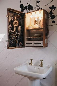 a bathroom with a sink, mirror and art on the wall above it's cabinet