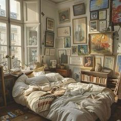 an unmade bed with many pictures on the wall