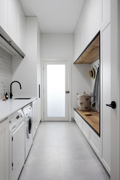 a white laundry room with washer and dryer next to the door that is open