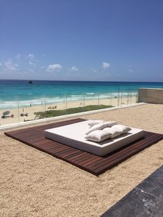 a bed sitting on top of a sandy beach next to the ocean