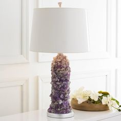 a lamp that is sitting on top of a table next to a vase with flowers