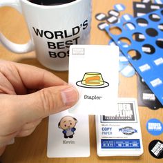 a person holding up a business card next to a coffee cup and other office supplies