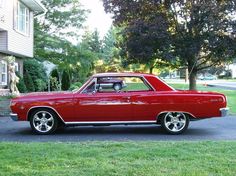 an old red car parked in front of a house