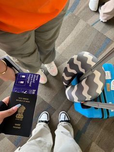 a person holding a passport and standing next to other people with their feet on the ground