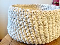 a crocheted basket sitting on top of a wooden table