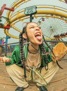 a woman with dreadlocks sitting on the ground in front of a carnival ride