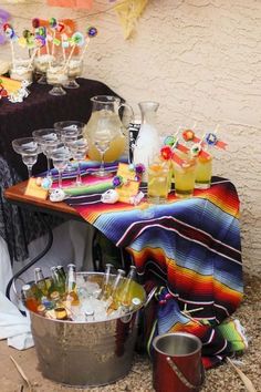 a table topped with lots of drinks next to buckets filled with ice and candy