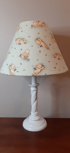 a white lamp with winnie the pooh print on it sitting on a wooden table