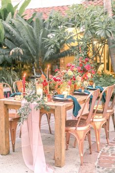 a table set up with flowers and candles for an outdoor dinner party in the garden