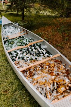 two canoes are lined up on the grass with ice and other things in them