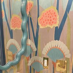 a bathroom wall with flowers painted on the walls and a blue pipe running through it