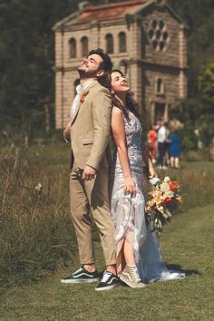 a bride and groom are standing in front of a house with their arms around each other