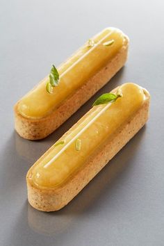 two pieces of food that are sitting on a table together, one is yellow and the other has green leaves