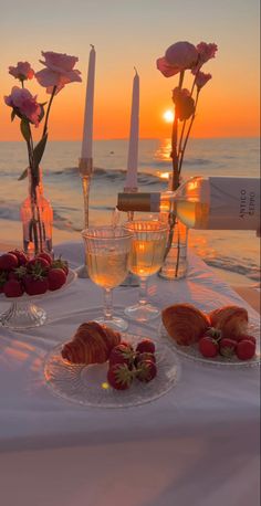 two plates with strawberries and croissants on a table near the ocean