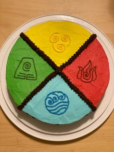 a cake decorated with four different colored shapes on a white plate and wooden table top