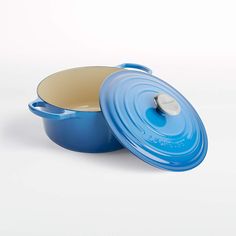 a blue casserole with a lid sitting on a white table next to it