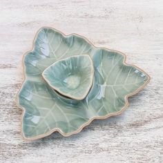 a green leaf shaped dish sitting on top of a wooden table