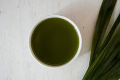 a cup of green tea next to some leaves