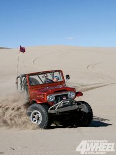 a red jeep driving through the sand dunes