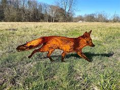 a metal sculpture of a fox running through a field