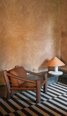 a chair and lamp in a room with a striped rug on the floor next to it