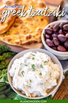 two bowls filled with dip, olives and pita bread on top of a table