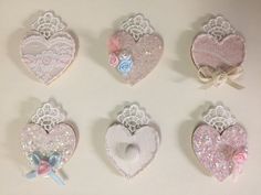 six heart shaped brooches with bows and lace on them, all decorated in pastel colors