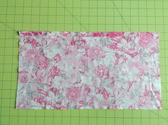 a piece of fabric with pink and white flowers on it next to a green cutting board