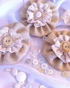 three pieces of fabric and buttons on a white table cloth with some flowers in the middle