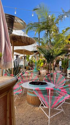 colorful chairs and umbrellas in an outdoor area with palm trees on the other side