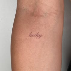 a woman's arm with the word lucky tattooed on her left side, in cursive font