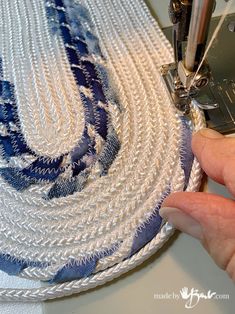 someone is using a sewing machine to sew a blue and white piece of fabric