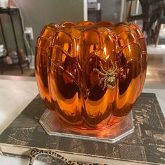 an orange glass vase sitting on top of a table next to a pair of glasses