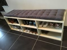 a bench with several pairs of shoes sitting on top of it in front of a tiled floor