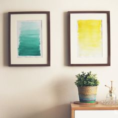 two paintings hang on the wall next to a dresser with a potted plant in it