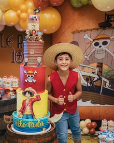 a boy in a sombrero standing next to a pirate themed cake with balloons