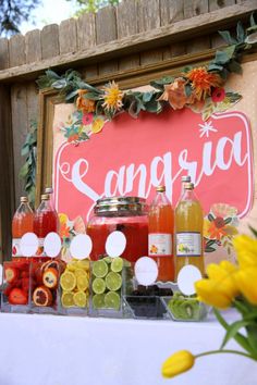 a table topped with lots of different types of drinks next to a sign that says sangria